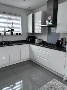 a white kitchen with white cabinets and a window at Double Room in a Family Home - 15 Minutes Walk to Famous Bicester Village in Chesterton