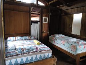 two beds in a room with wooden walls at Casa Colibri in Nuquí