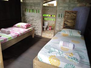 two beds in a room with a bathroom at Casa Colibri in Nuquí