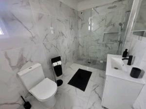 a white bathroom with a toilet and a sink at The Believers - Porto Santo in Porto Santo