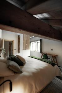 um quarto grande com uma grande cama branca com almofadas em La Loge de la Dolarde - Chambre Nord-Est em Prémanon
