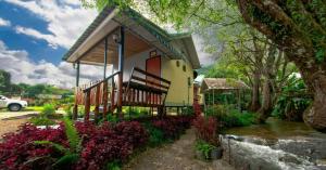 una casa con un porche y flores delante de ella en Inthanon Lao-Ju House en Chom Thong