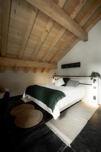 a bedroom with a large white bed and wooden ceilings at La Loge de la Dolarde - Chambre Nord-Est in Prémanon