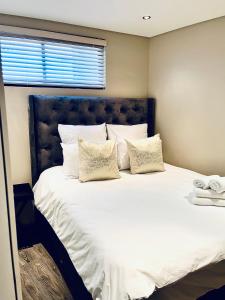 1 dormitorio con 1 cama grande con sábanas y almohadas blancas en ModernLuxe Apartment en Windhoek