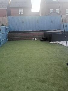 a small backyard with a grass lawn and a fence at Burton House 