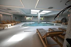 uma grande piscina num quarto com cadeiras em Hotel Tamiš & Spa em Pančevo