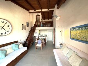 sala de estar con reloj en la pared en Punta Est Trilocale Soppalco con Terrazza Vista Mare, en Capo Coda Cavallo