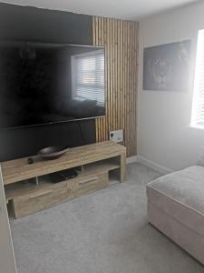 uma sala de estar com uma grande televisão de ecrã plano em Burton House 
