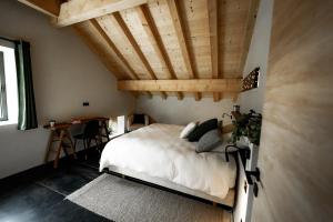 um quarto com uma cama e um tecto de madeira em La Loge de la Dolarde - Chambre Nord-Est em Prémanon
