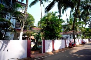 a street sign in front of a building with palm trees at Goa Divine Candolim in Calangute