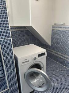 y baño con lavadora y azulejos azules. en Freundliche Wohnung Nähe Weinstraße für 5 Personen, en Wagna