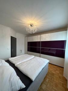 1 dormitorio con 2 camas blancas y lámpara de araña en Freundliche Wohnung Nähe Weinstraße für 5 Personen, en Wagna