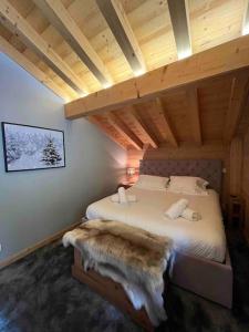 ein Schlafzimmer mit einem großen Bett in einer Holzdecke in der Unterkunft Chalet Balata - Charming chalet with hot tub and views in La Côte dʼArbroz