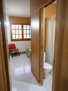 a bathroom with a toilet and a room with a table at CASA MANOLO CAMIÑO DO SANTIAGUIÑO in Vedra