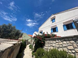 a house with a stone wall and flowers on it at House Mateja Unije in Unije