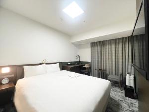 a hotel room with a large white bed and a desk at Richmond Hotel Fukuyama Ekimae in Fukuyama
