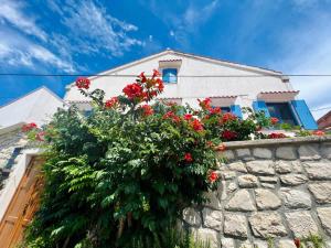 a house with red flowers on a stone wall at House Mateja Unije in Unije
