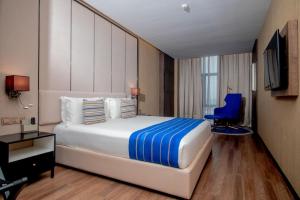 sypialnia z dużym łóżkiem i niebieskim krzesłem w obiekcie CIKA GOLDEN HOTEL and SUITES w mieście Lomé