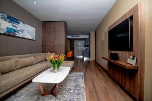 a living room with a couch and a tv and a table at CIKA GOLDEN HOTEL and SUITES in Lomé
