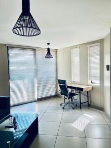 an office with a desk and a chair and windows at ModernLuxe Apartment in Windhoek