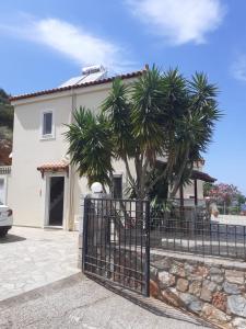 une maison blanche avec des palmiers devant une clôture dans l'établissement Villa Calli, à Mália