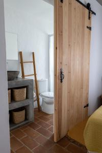 a bathroom with a toilet and a wooden door at Sunrise Monsaraz Green - 1km Castelo Monsaraz com telheiro e jardim in Monsaraz +42 photos