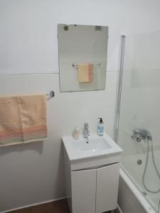 a white bathroom with a sink and a shower at Simpático apartamento no centro in Lisbon