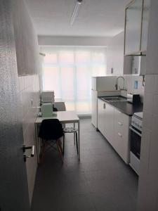 a white kitchen with a table and a chair at Simpático apartamento no centro in Lisbon