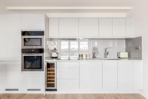 a white kitchen with white cabinets and appliances at The Camden Apartment in London