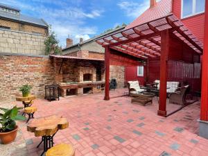a patio with a brick wall and a wooden pergola at Karlsons apartment in Liepāja