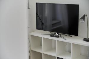 TV de pantalla plana en un estante blanco en Studio Jedności Narodowej Wrocław by Renters, en Wroclaw