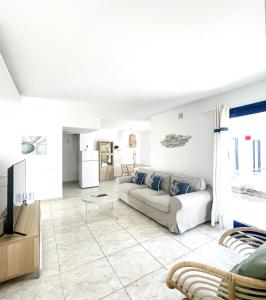 un soggiorno bianco con un divano e una TV di Los Barqueros 24 by Best Holidays Fuerteventura a Corralejo