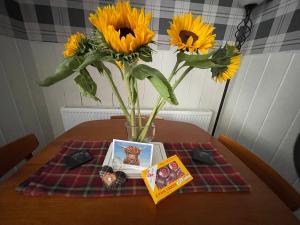 a vase with sunflowers and a book on a table at Moulin Cottage in Moulin