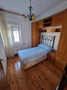 1 dormitorio con 1 cama, suelo de madera y lámpara de araña. en APARTAMENTO SUJARRERA, en Villacarriedo