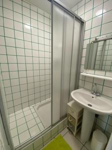 ein weiß gefliestes Bad mit einem Waschbecken und einer Dusche in der Unterkunft Chambres du Vau-Nogues in Pleudihen-sur-Rance