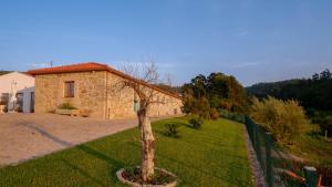 uma pequena casa de pedra com uma árvore num quintal em Quinta de Real em Valença