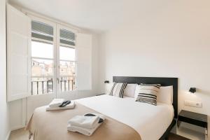 a white bedroom with a large bed and a window at BCN Town Apartments Portaferrissa in Barcelona