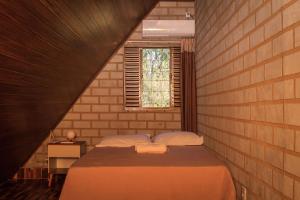 um quarto com uma cama numa parede de tijolos em Chale elegante c hidromassagem no Alto Paraiso GO em São Jorge