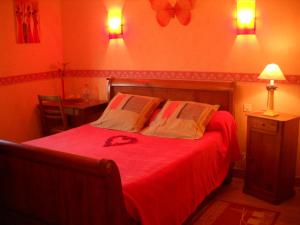 Un dormitorio con una cama roja con dos almohadas. en Chambres du Vau-Nogues, en Pleudihen-sur-Rance 2 fotos más
