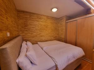 een kleine slaapkamer met een bed en een houten muur bij Apartman Lord Aparthotel Vučko in Jahorina