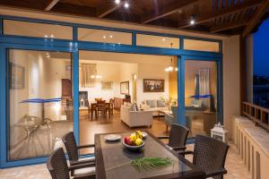 ein Esszimmer und ein Wohnzimmer mit Glasschiebetüren in der Unterkunft Captain's House Hotel Suites & Apartments in Panormos