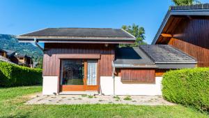 a small house with a wooden door in a yard at 35 CHALET - Chalet lumineux 6 pers in Morillon