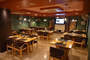 a restaurant with wooden tables and chairs and a television at karisma premium in Bhubaneshwar