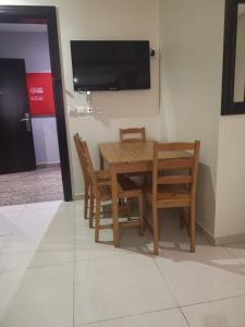 a wooden table and chairs with a television on a wall at راما للاجنحة الفندقية in Jeddah
