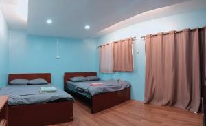 two beds in a room with blue walls at Inthanon Lao-Ju House in Chom Thong