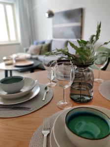 a wooden table with plates and wine glasses on it at Trendy apartment in the heart of green Lahti, free parking in Lahti