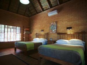 1 Schlafzimmer mit 2 Betten und Ziegelwand in der Unterkunft Mokuru Private Nature Reserve in Brits