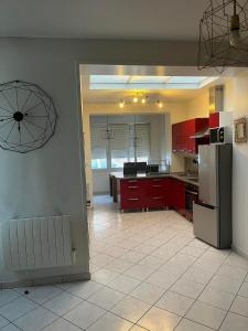 eine Küche mit roten Schränken und weißen Fliesenböden in der Unterkunft La brique rouge - Maison 66 m2 avec 2 chambres in Lille
