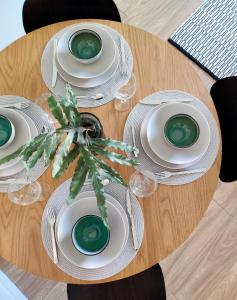 a wooden table with plates and a plant on it at Trendy apartment in the heart of green Lahti, free parking in Lahti +15 photos