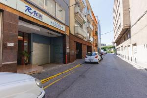 une voiture blanche garée sur le côté d'une rue dans l'établissement Bravissimo Figuerola, Spacious 3-bedroom apartment, à Gérone